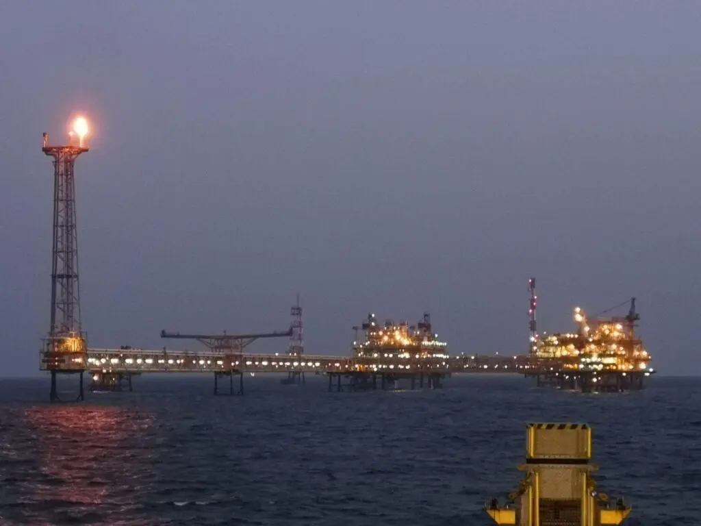 Bravo North Field offshore gas platform at night, illuminated oil and gas production facility with flare tower and interconnected structures in open sea